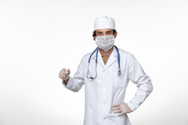 冠状病毒正面图身穿医疗服的男医生戴着口罩 以防白墙病毒疾病传播冠状病毒防护听诊器视图