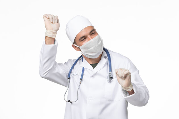 实验室外套正面图男医生穿着医疗服 戴着口罩 因在白墙上跳舞而患上了冠状病毒大流行性病毒病男性到期外套