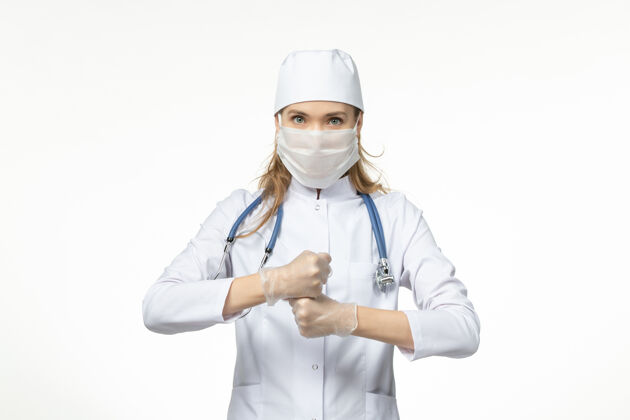 医生正面图女医生穿着医疗服 戴着口罩和手套 由于白色办公桌上的冠状病毒疾病大流行健康冠状病毒手套听诊器冠状病毒