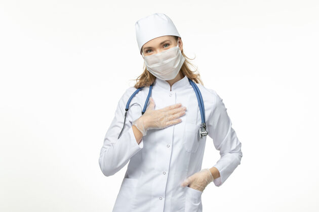 护士正面图女医生穿着医疗服戴着口罩和手套 因白墙上冠状病毒病大流行药品女性正面
