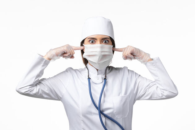 外套正面图女医生穿着白色医疗服 戴着口罩 因大流行闭上了耳朵 白桌上的病药病毒大流行 可维-大流行套装实验室外套