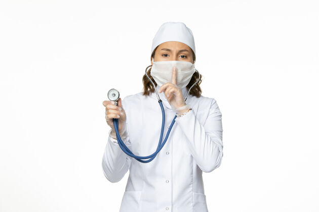 外套正面图女医生穿着白色医疗服 戴着口罩在白色办公桌上使用听诊器大流行病毒疾病药物口罩专业使用