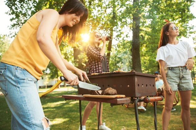 一天一群快乐的朋友在阳光明媚的日子里喝着啤酒 一起烧烤一起在户外的林间空地或后院休息啤酒后院休闲