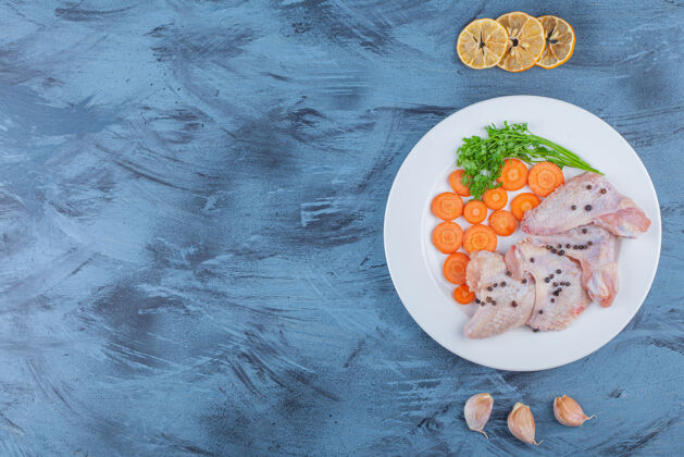 开胃菜把腌好的鸡翅和各种蔬菜放在蓝色的盘子里肉海洋禽类