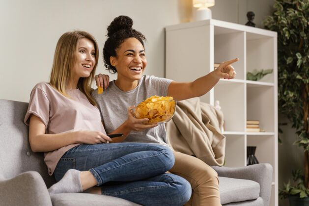 休闲坐在沙发上看电视吃薯片的女人女人沙发看电视