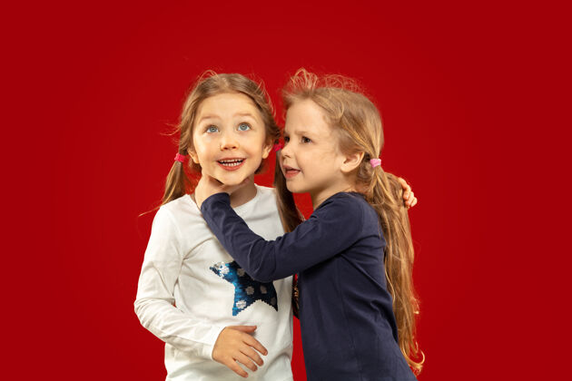 玩美丽动情的小女孩被隔离在红色空间里快乐的姐妹或朋友站着微笑的半身肖像人类漂亮小