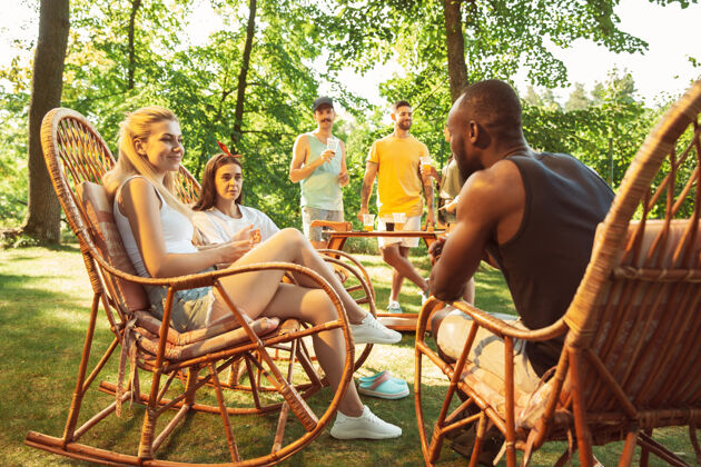 肉一群快乐的朋友在阳光明媚的日子里喝着啤酒 一起烧烤一起在户外的林间空地或后院休息食物自然家庭