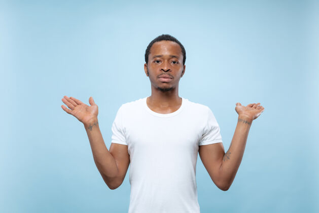 就业半身特写肖像的年轻非洲裔美国男子在白色衬衫的蓝色空间人类的情感 面部表情 广告概念男人选择长度