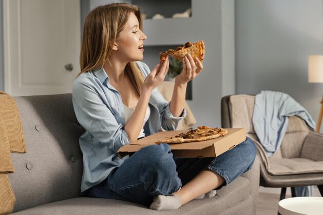 室内女人一边看电视一边吃比萨饼女人女人披萨