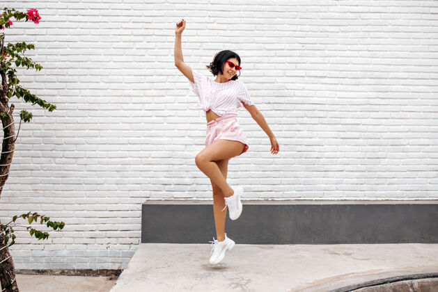 花穿白色运动鞋的女人在街上跳跃跳舞的女人享受夏天的全景女人减肥魅力