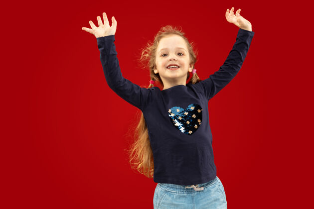 表情美丽动情的小女孩被隔离在红色的空间里快乐的孩子微笑跳舞的半幅肖像积极金发孩子