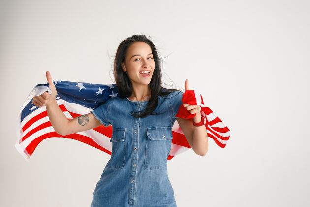 美国庆祝独立日星条旗白色工作室墙上挂着美国国旗的年轻女子看起来像个疯狂的快乐和自豪的爱国主义者七月现代广告
