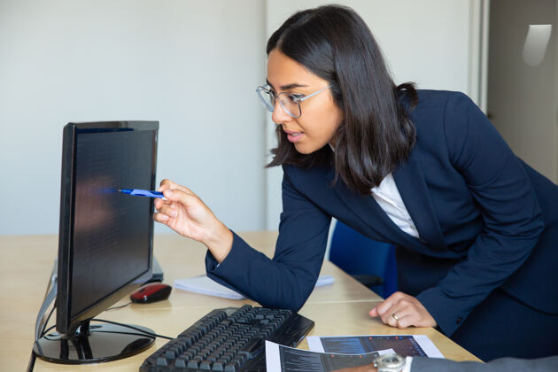 投资者专注的女性专业人士用钢笔指着显示器上的统计报告 靠在办公桌上放着财务图表中镜头财务顾问概念公司员工会议