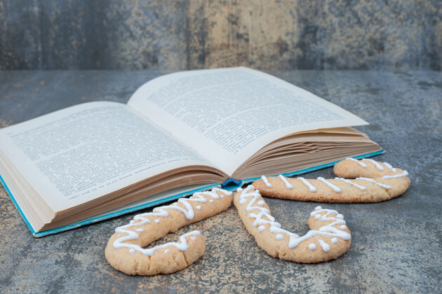 甜点三个姜饼饼干和打开大理石背景上的书高品质的照片饼干糖果食物