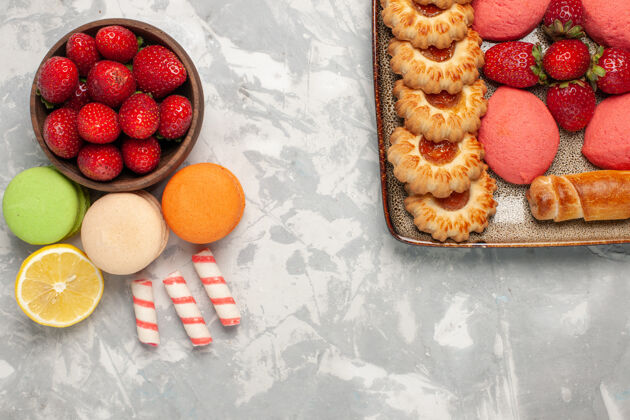顶部顶视图法国马卡龙与新鲜的红色草莓在白色的表面一餐新鲜可食用的水果