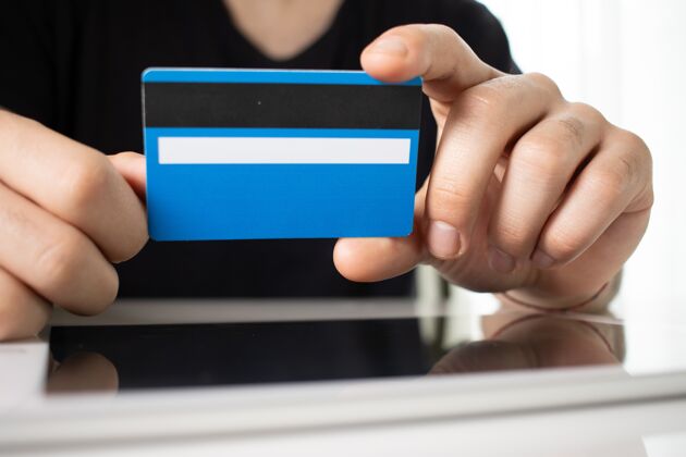 现金一个人的手拿着一张蓝色的信用卡在一个白色房间的反射面上金融美元购买