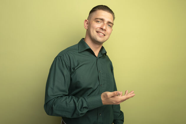 衬衫一个穿着绿衬衫的年轻帅哥 用他的手臂微笑着展示着什么手臂光微笑