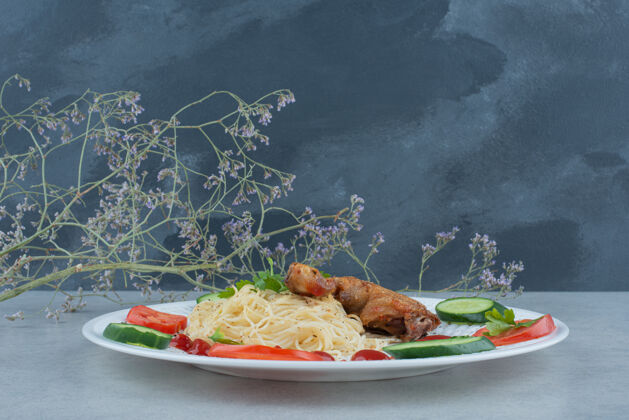 意大利面白色盘子上的蔬菜沙拉 大理石背景上有意大利面和鸡肉美味黄瓜鸡肉