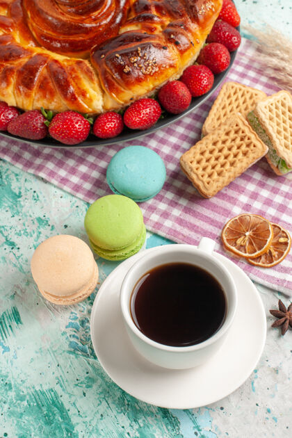 茶俯瞰美味的派与一杯茶和新鲜的红色草莓在蓝色的表面饮料热的咖啡