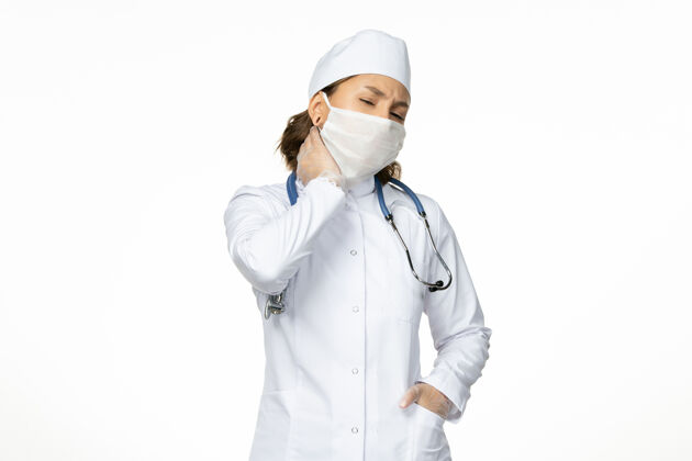 口罩正面图年轻女医生 戴着消毒口罩和手套 因为冠状病毒在白色表面有颈部疼痛女性颈部疼痛手套