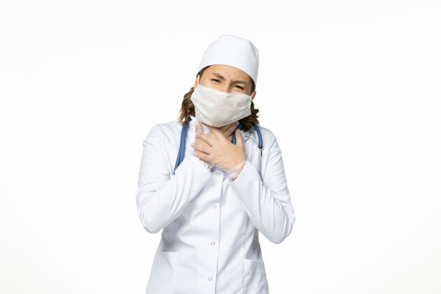 大流行正面图年轻女医生戴着无菌口罩和手套 由于冠状病毒在浅白的表面耳机专业到期