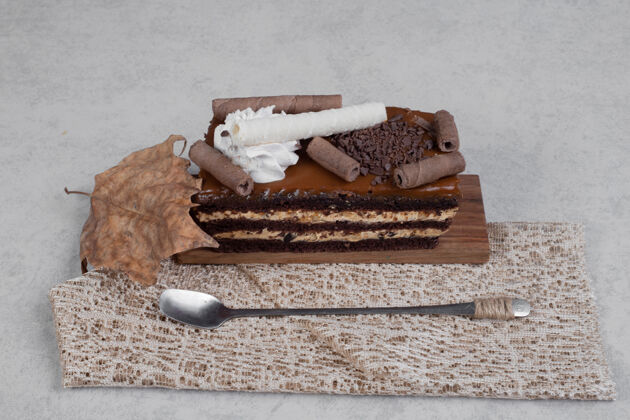 切片在大理石桌上用叶子和勺子切巧克力蛋糕高质量的照片面包房粗麻布巧克力