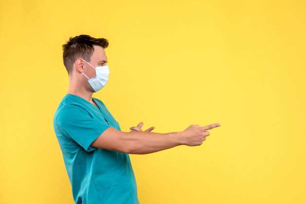 面具黄墙上戴着无菌口罩的男医生的正视图情感男医生医学