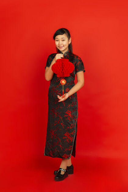 传统新年快乐红色背景上孤立的亚洲少女肖像穿着传统服装的女模特看起来很开心 带着装饰微笑庆祝 节日 情感肖像喜悦微笑