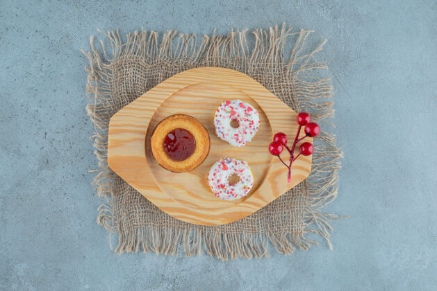 美味小吃大小的甜甜圈和果冻填充蛋糕放在大理石背景的木盘上高品质照片糕点甜点蛋糕