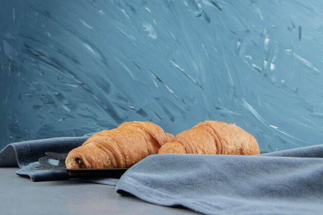 牙粉美味的牛角面包在毛巾上 在蓝色的背景上高品质的照片甜味毛巾奶油