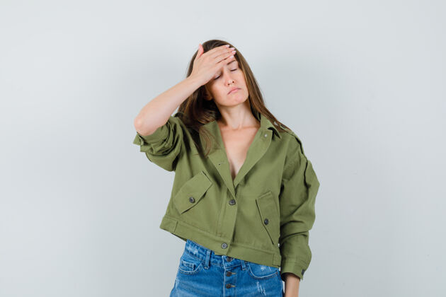 积极穿着绿色夹克的年轻女性 短裤手放在额头上 看起来很累 前视图休闲年轻时尚