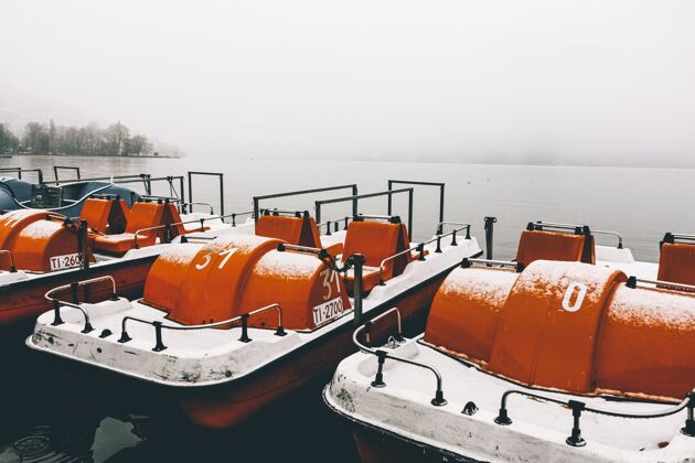 木头在一个雾蒙蒙的冬日 平静的湖面上 码头边的橙色划艇被捕捉到了码头雾景观