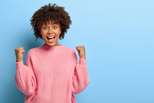 快乐一个穿着粉色毛衣的非洲裔快乐女人人快乐享受