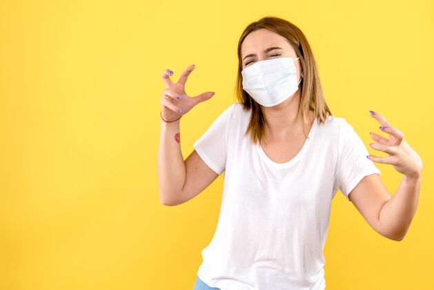 微笑黄色墙壁上戴着无菌口罩的年轻女子的正视图医学成人病毒