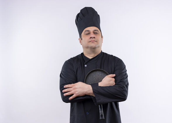 平底锅男厨师身穿黑色制服 头戴厨师帽 举着平底锅 闭着眼睛站在白色背景上制服帽子持有