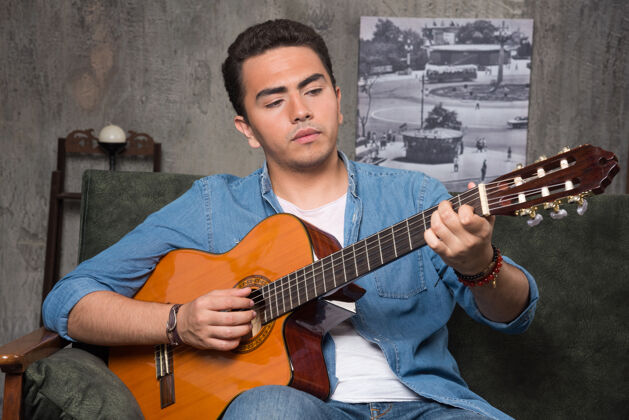 玩年轻的音乐家弹吉他 坐在沙发上高品质的照片乐器吉他手肖像