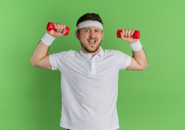 紧张身穿白衬衫 头箍戴着哑铃 紧张地站在绿色背景下锻炼身体的年轻人健身白色男士