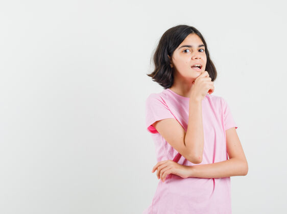 漂亮小女孩站在思考的姿势在粉红色的t恤衫 并期待好奇前视图未成年人年轻