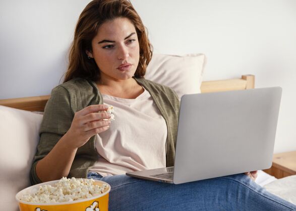 室内女人一边吃爆米花一边用笔记本看电影爆米花科技吃