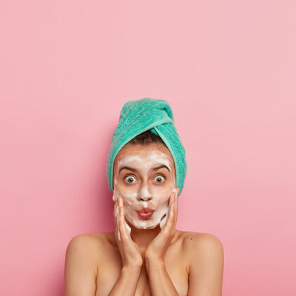 圆形护肤常规和卫生概念照片中的可爱的女人睁大眼睛 保持嘴唇折叠 按摩脸颊和应用泡沫肥皂人自然产品