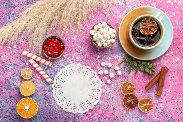 生料顶视图一杯茶 白色的甜心和肉桂放在粉红色的桌子上饰品甜糖果