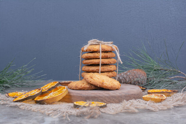 甜点木盘上放着燕麦片饼干 周围放着干橙子片奶油精致面粉