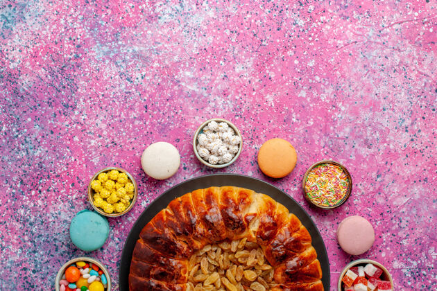 糖顶视图五颜六色的法国马卡龙小美味蛋糕与糖果和葡萄干馅饼在粉红色的桌子上糖烤饼干饼干馅饼麦卡龙菜餐