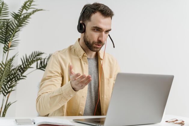 笔记本电脑戴着耳机的男人在笔记本电脑上进行视频通话学习耳机男