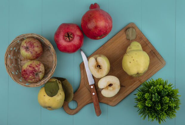 整个顶视图新鲜的一半苹果在木制厨房板与刀与整个苹果桶与木瓜隔离在一个蓝色的背景顶部水果蓝色