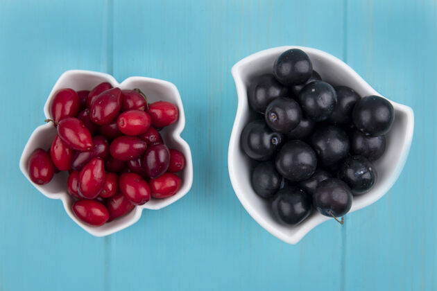 树莓蓝色背景上碗里的山茱萸和树莓水果俯视图山茱萸水果碗