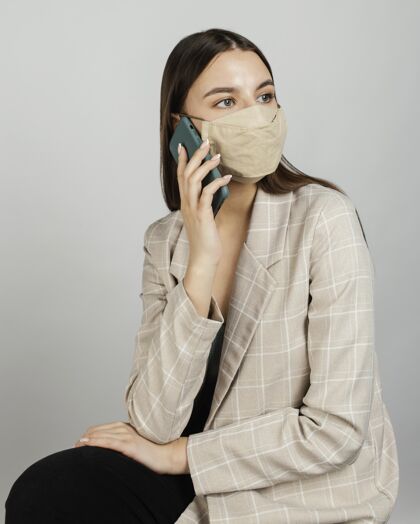 说话肖像时尚的女人用手机带面具预防冠状病毒保护