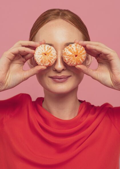 食物用橘子遮住眼睛的女人饮食美丽吃