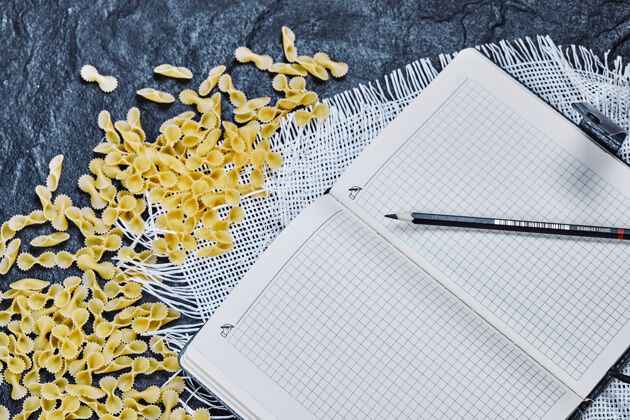 大理石生面食 笔记本和铅笔放在大理石表面生的烹饪笔记本