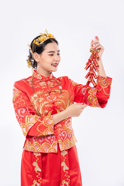 中国民族女人穿旗袍套装笑着从老板那里得到鞭炮在中国新年旗袍欢呼中国新年